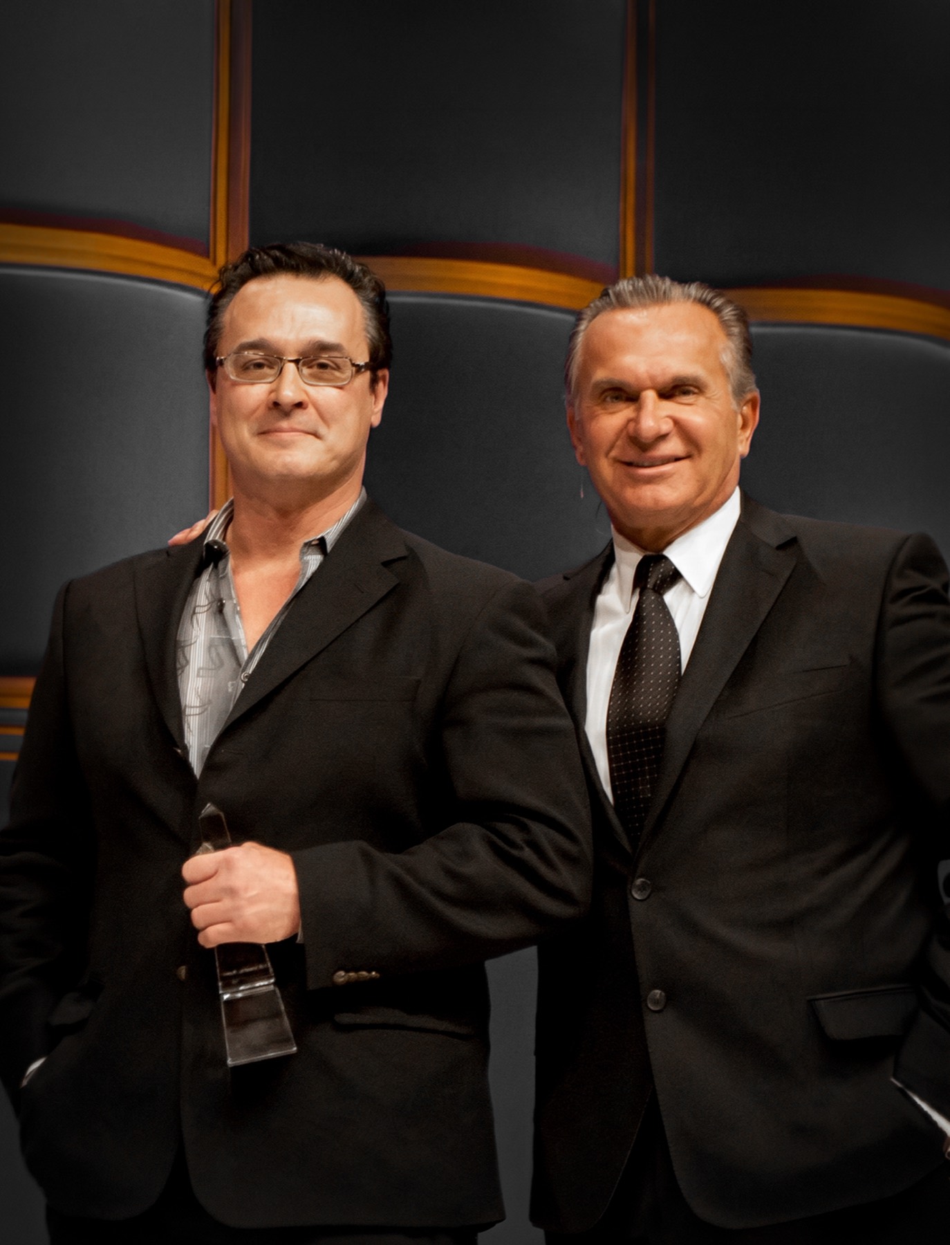 Two clinicians in dark suits holding a crystal trophy at the Aesthetics Awards ceremony