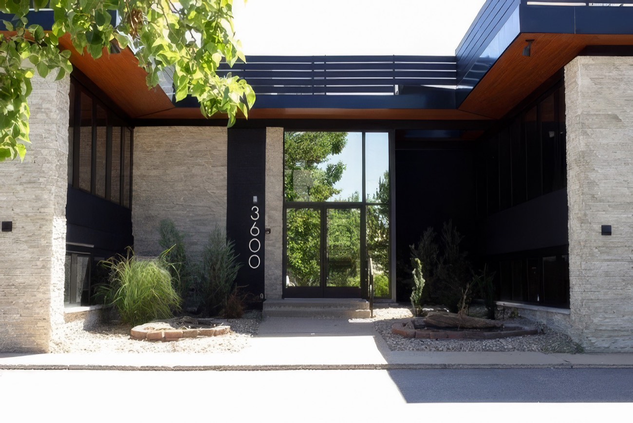 Glass and stone entrance of the clinic at 3600, framed by a timber-lined canopy
