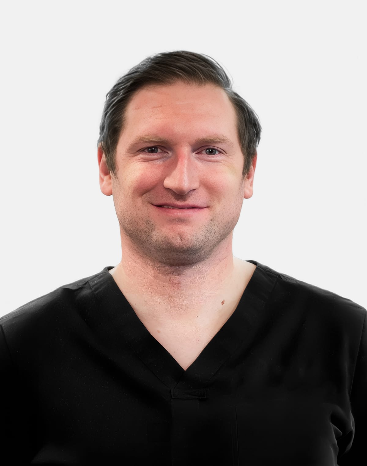Dr. David Kowalczyk in black scrubs, smiling against a light grey background